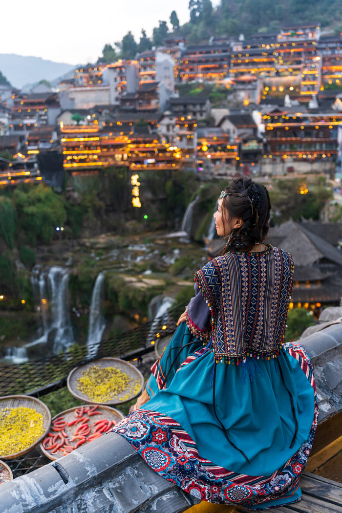 mujer sentada en un borde observando la ciudad de lijiang